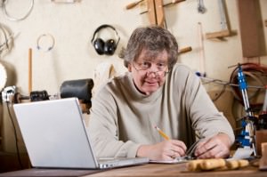 Craftsman in workshop using laptop